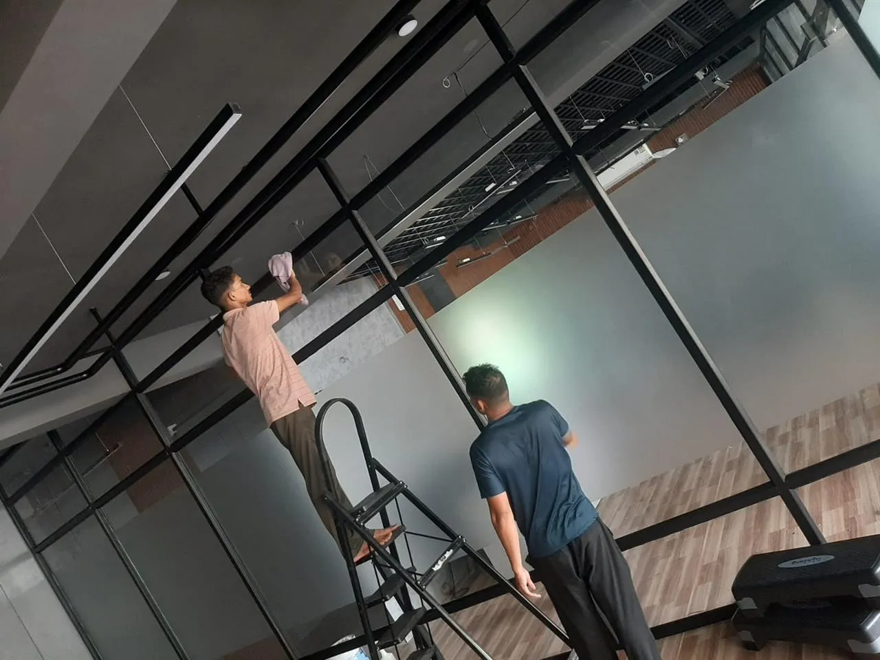 GetPros cleaners working on glass partitions with a ladder and cleaning tools
